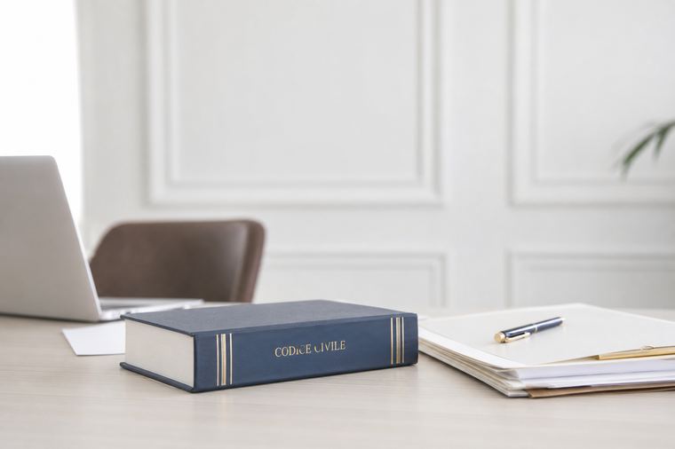 Un uomo in abito bianco lungo legge un libro aperto tenendolo tra le mani.